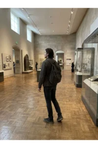 A visitor in an exhibit gallery with old objects and display cases.