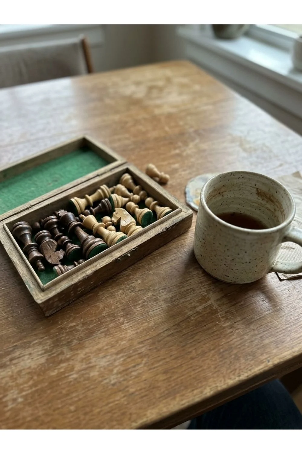 A chessboard set up beside a mug at a café table.